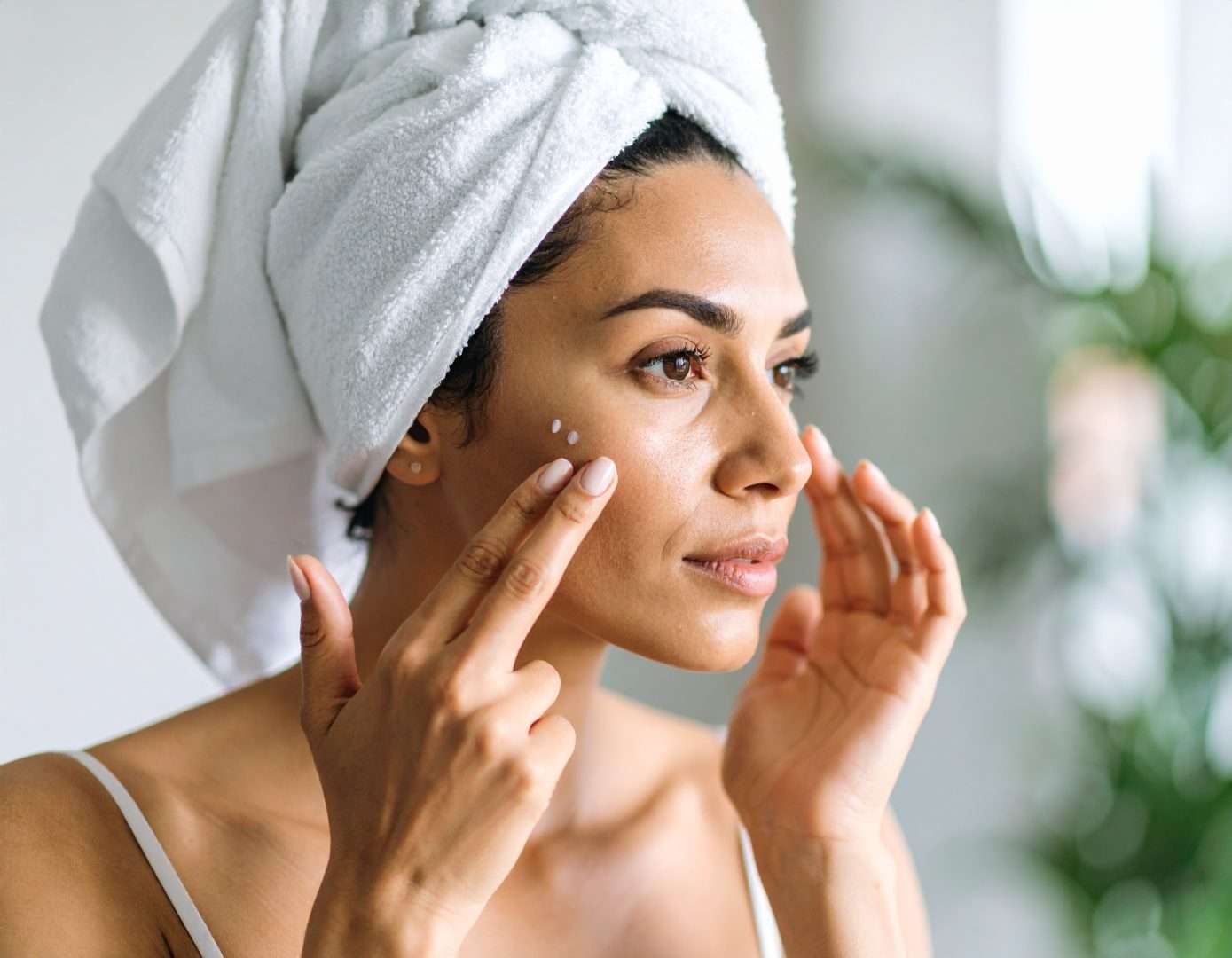 Mujer con toalla de baño aplicando productos en su rostro